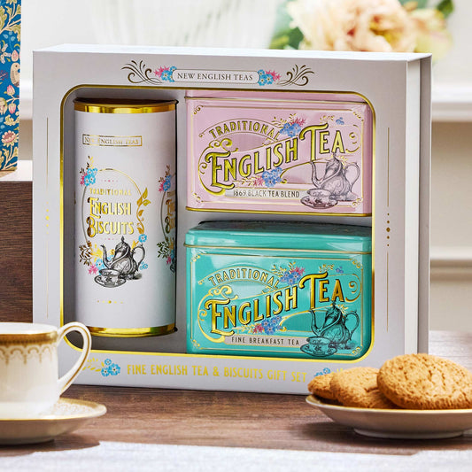 Tea and biscuit gift set in a white box with English Biscuits, black blend and breakfast tea tins, styled with a teacup and biscuits on a wooden table.