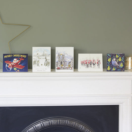 Collection of Christmas cards that make up this Bargain Pack on a white mantelpiece against a grey wall.