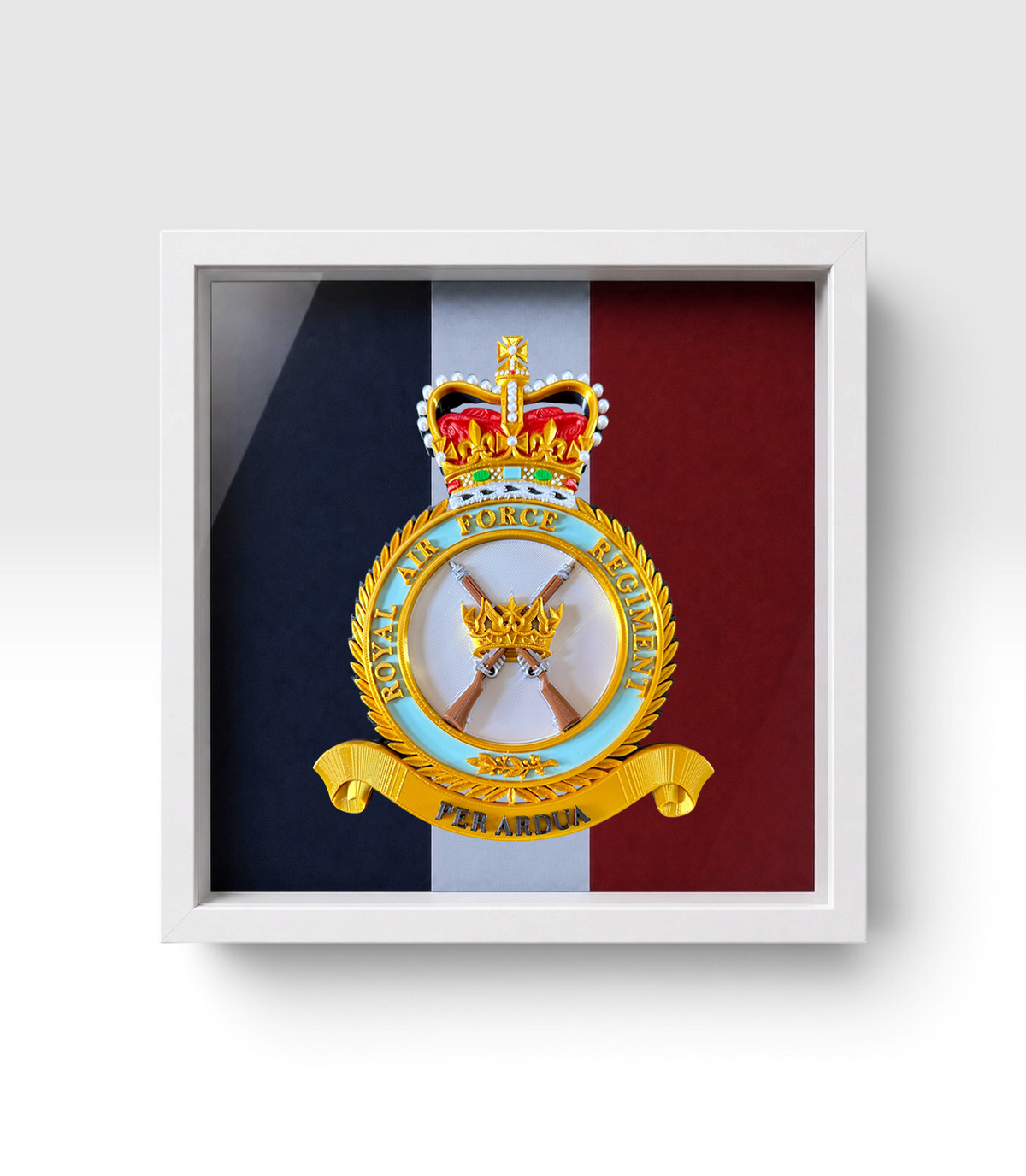 A white framed, military crest of the RAF Regiment (Queen's Crown) insignia, displayed against a professionally pigment-printed RAF Regiment backing, in a white shadowbox frame.