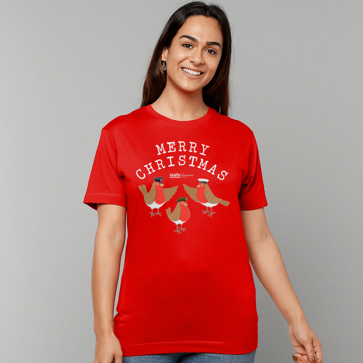 A woman wearing a red crewneck t-shirt featuring a 'MERRY CHRISTMAS' graphic with three cartoon robins underneath wearing Army, Royal Navy and RAF military hats.
