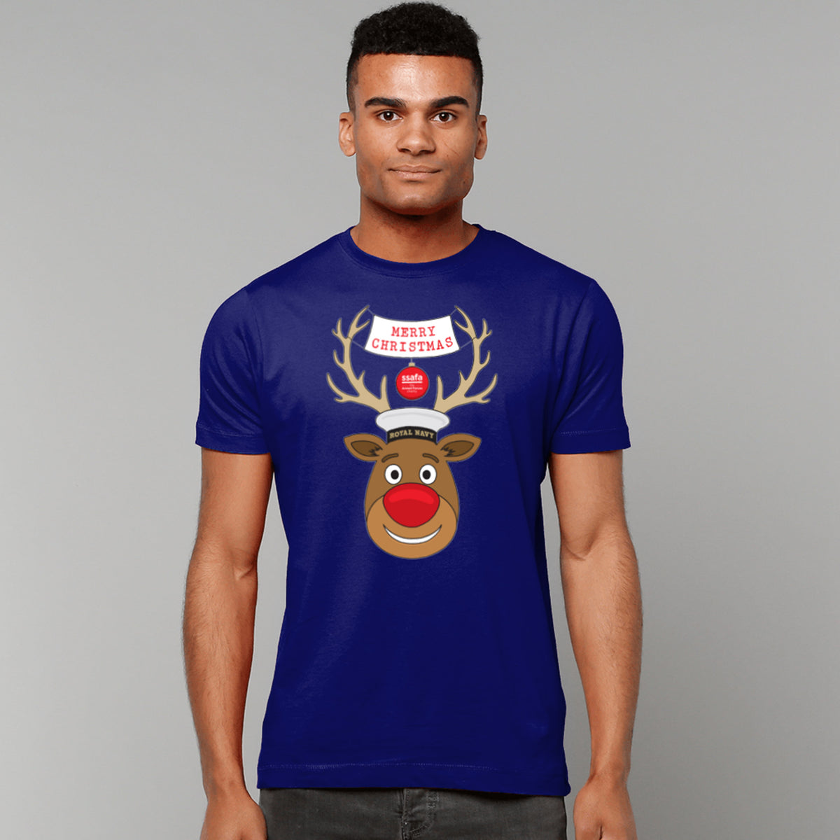 A man wearing a navy short-sleeve crewneck t-shirt featuring a cartoon graphic of a reindeer with brown antlers, a red nose, wearing a Royal Navy pork pie hat. A banner reads 'MERRY CHRISTMAS'.