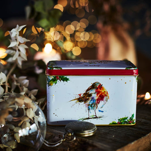 Tea Tin with painting of Christmas Robin. Tin on a wooden block with blurred Christmas lights in the background.