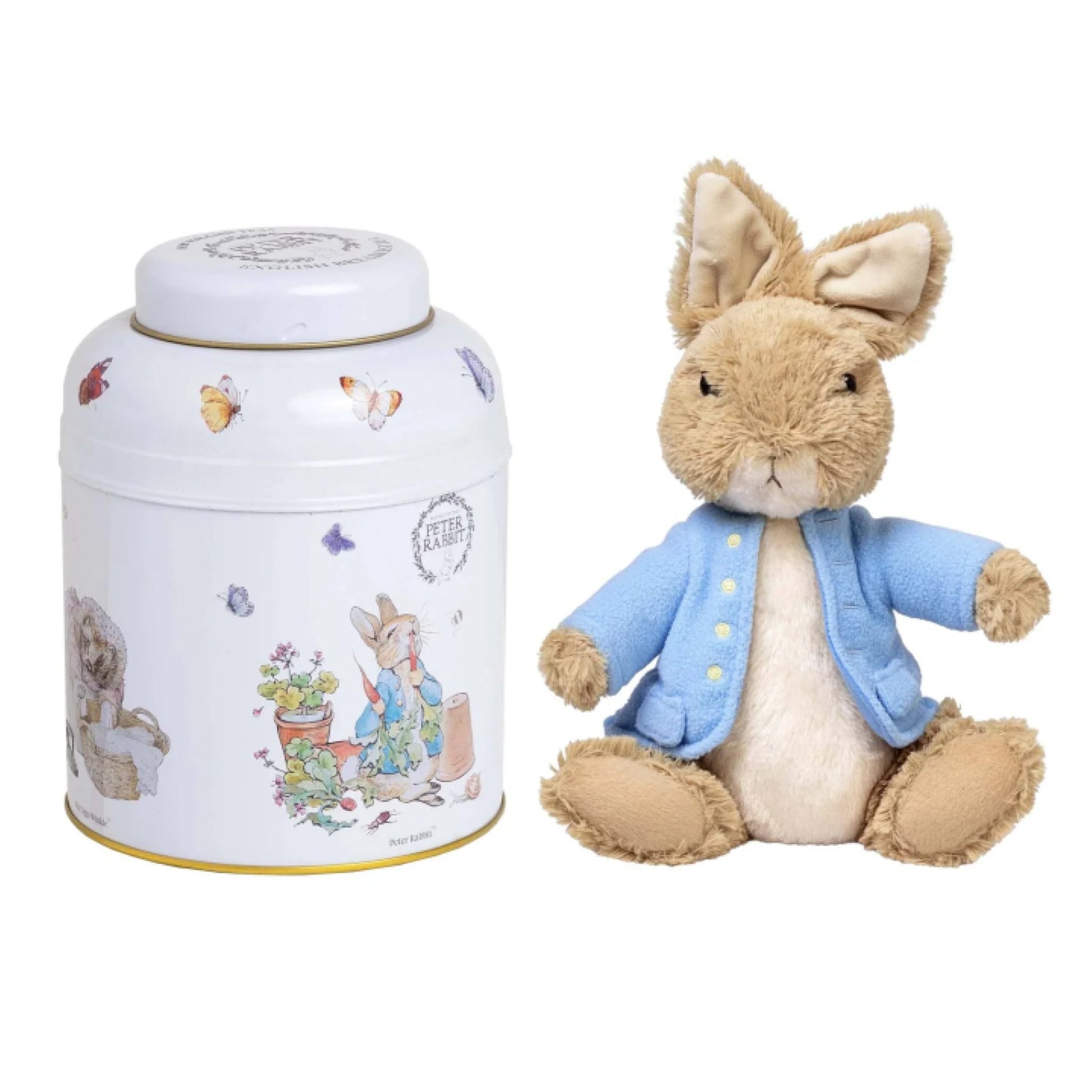A Peter Rabbit collectible set featuring a plush toy Peter Rabbit in a blue jacket next to a white metal tin decorated with Peter Rabbit illustrations.