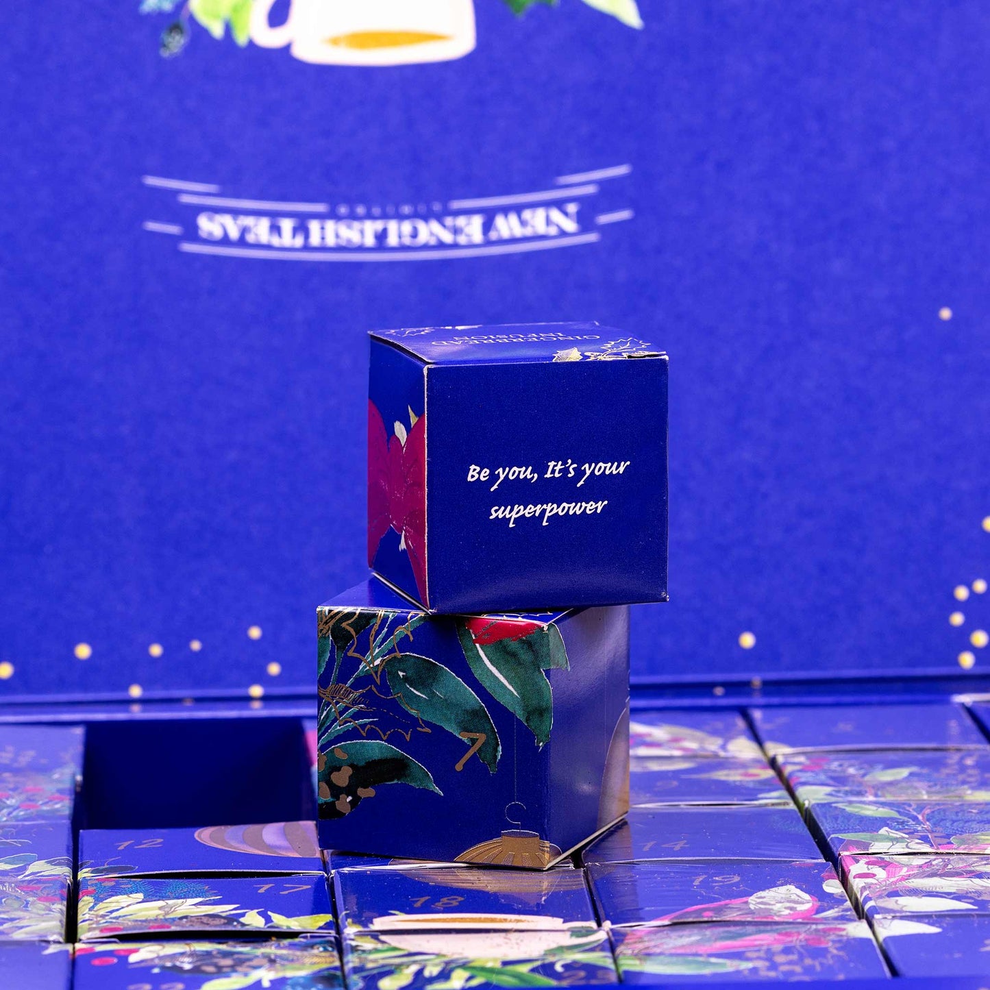 Blue decorative box with floral design and motivational quote on a reflective surface with a blue background. Showing individual advent boxes for each day.