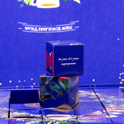 Blue decorative box with floral design and motivational quote on a reflective surface with a blue background. Showing individual advent boxes for each day.
