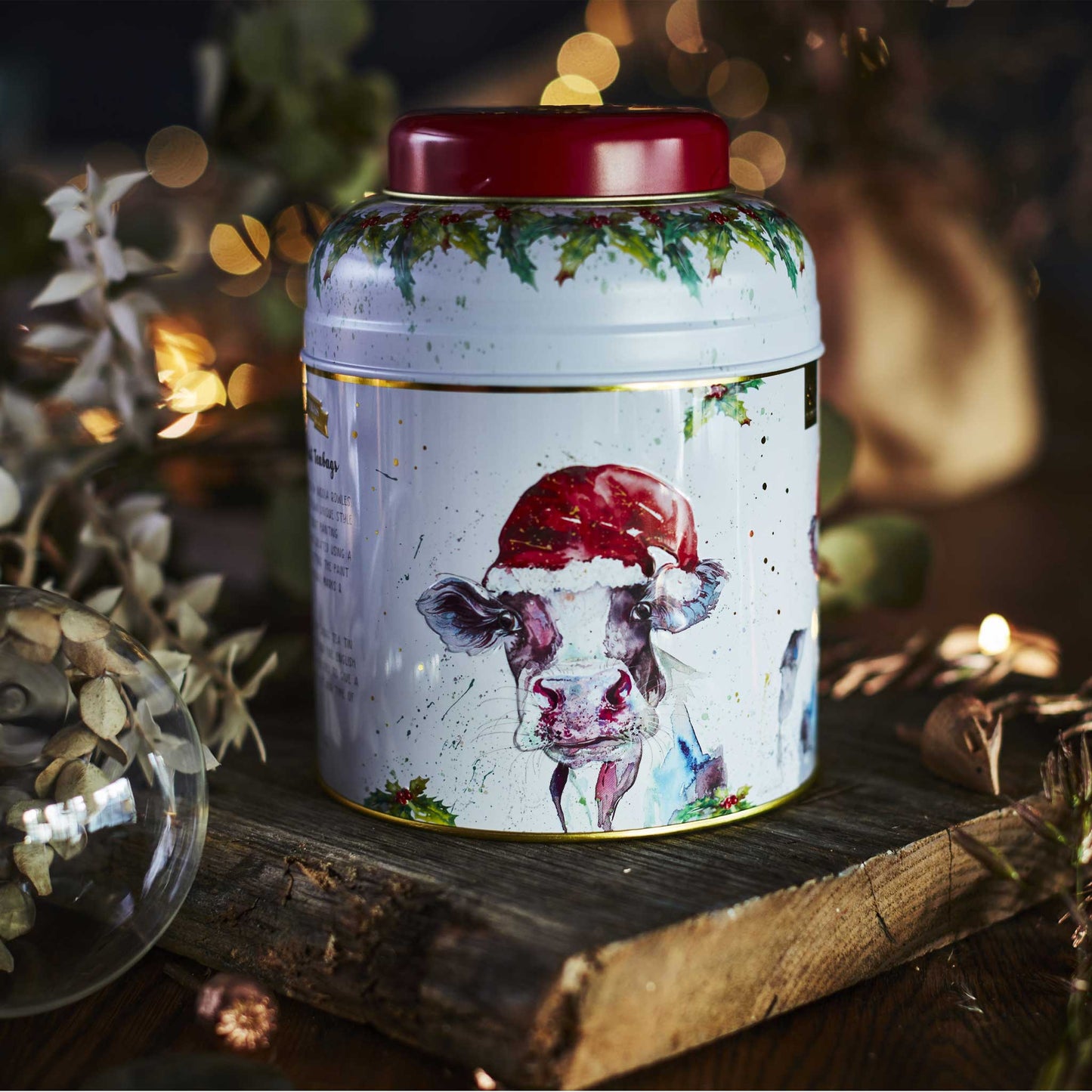 Nicola Rowles 80 Teabag Caddy Bluebell the Christmas Cow in Christmas setting with baubles and sparkly lights.