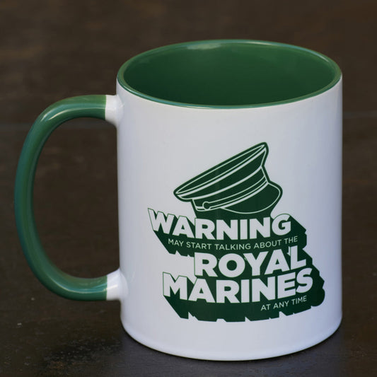 White mug with green interior and handle, featuring a military hat graphic and text reading: Warning may start stalking about the Royal Marines at any time. Set against a dark metallic background.