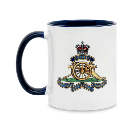 A white ceramic mug with a navy handle and interior, featuring a printed insignia of the Royal Artillery on the front. Set against a plain white background.