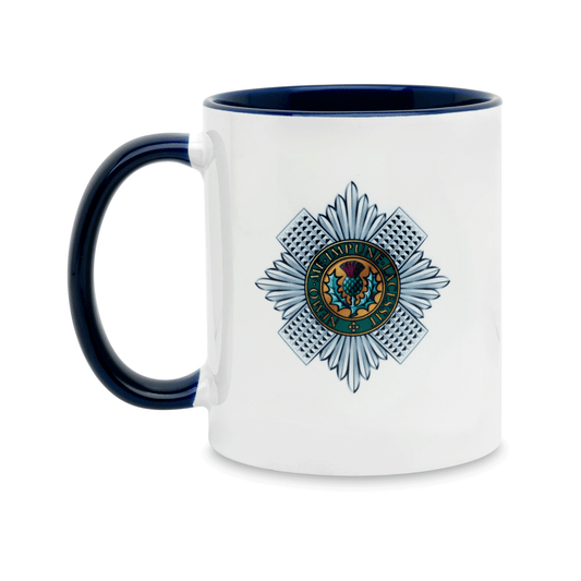 A white ceramic mug with a navy handle and interior, featuring a printed insignia of the Scots Guards on the front. Set against a plain white background.