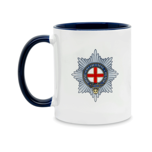 A white ceramic mug with a navy handle and interior, featuring a printed insignia of the Coldstream Guards on the front. Set against a plain white background.
