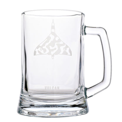 A clear glass beer mug with a handle, featuring an etched gray delta-shaped logo with a camouflage pattern and the word 'VULCAN' near the base, shown on a white background.