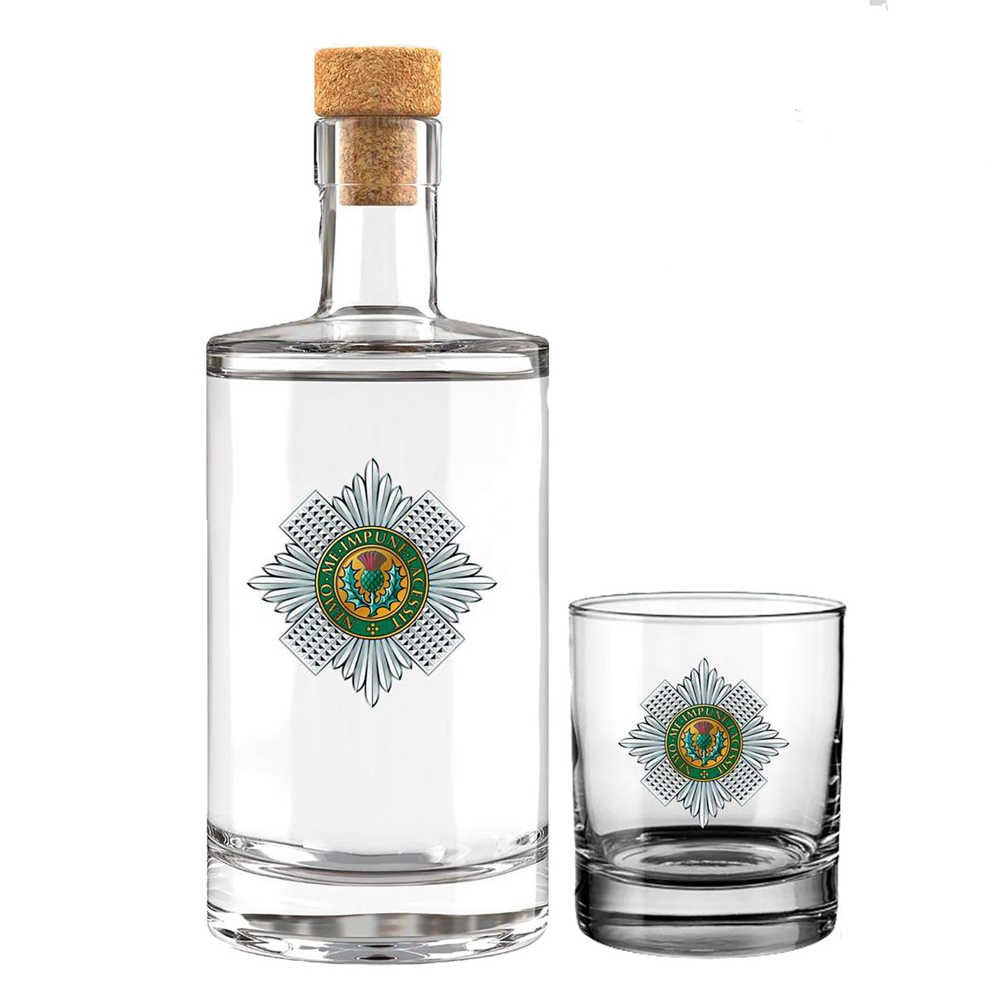 A clear glass bottle with a cork stopper and a matching small clear glass tumbler, both printed with the insignia of thr Scots Guards featuring a green and gold center surrounded by grey rays. The bottle is larger than the tumbler and shown on a plain white background.