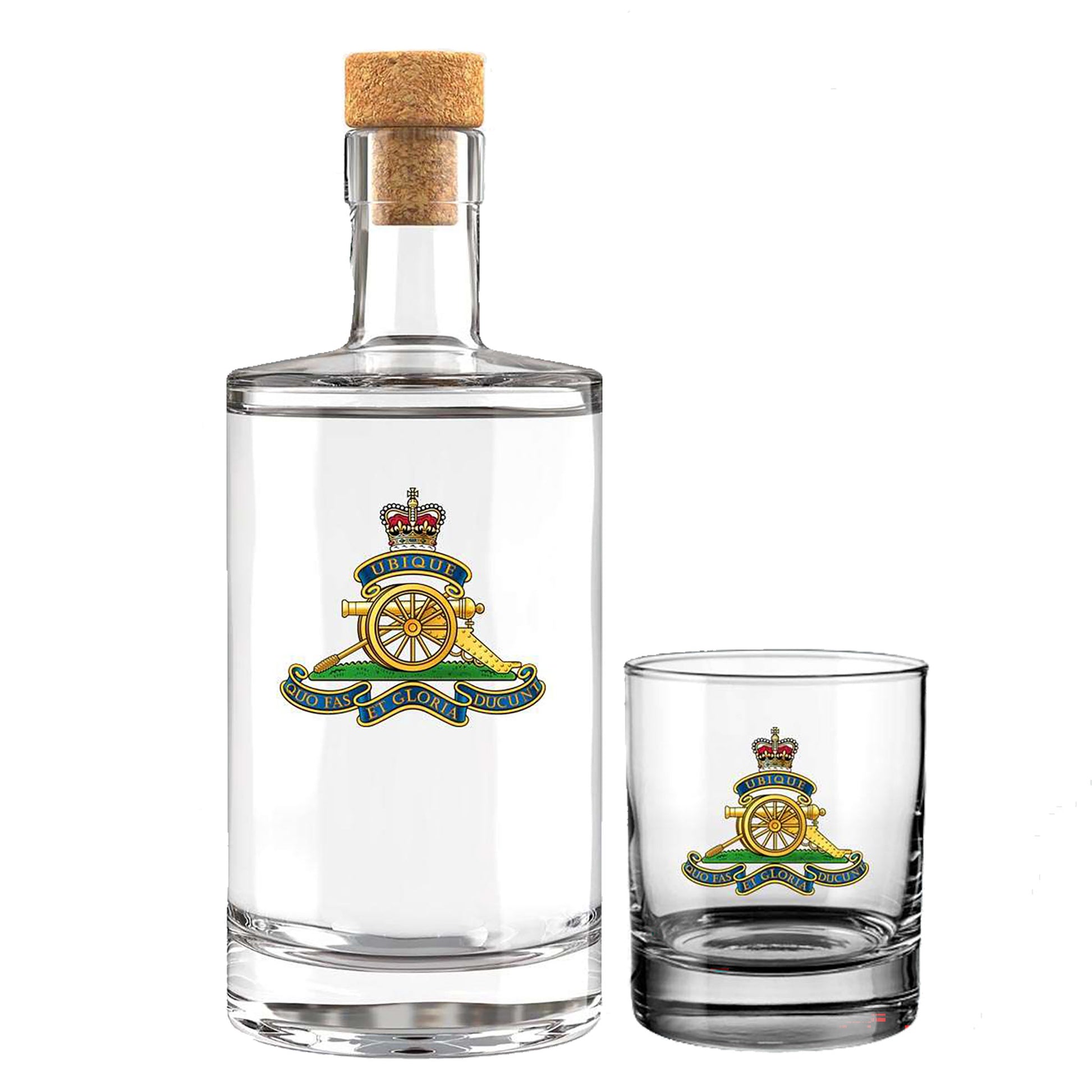 A clear glass bottle with a cork stopper and a matching clear glass tumbler, both printed with  the insignia of the Royal Artillery. The bottle is larger than the tumbler and shown on a plain white background.