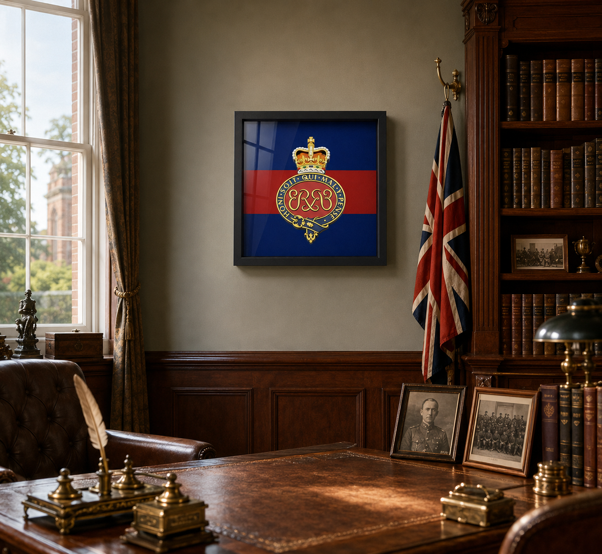 A framed Grenadier Guards (Queen's Crown) insignia displayed on a beige wall in a vintage, book-filled study with a wooden desk, leather chair, and union flag.