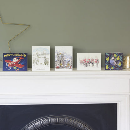 Collection of Christmas cards that make up this Bargain Pack on a white mantelpiece against a grey wall.