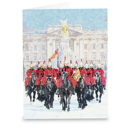 Horse Guards in red uniforms on horseback in front of Buckingham Palace in the snow.