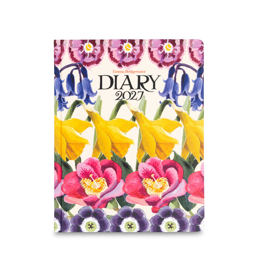 A floral illustrated diary cover with the title 'Emma Bridgwater DIARY 2027' in the center. The design features spring flowers including purple violins, yellow daffodils, and pink blossoms on a light cream background.