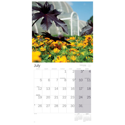 A vertical wall calendar page showing a large scenic photograph of a flower field with yellow blooms and dark purple leaves above a printed July calendar grid on a white background.