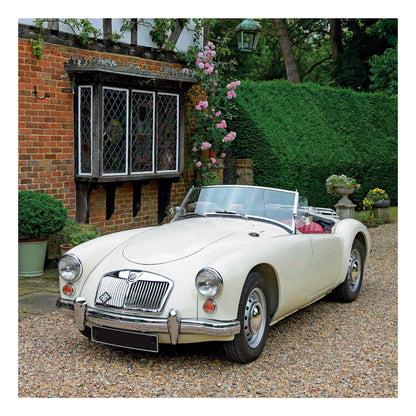 A cream MGA 1600 Roadster from 1959 vintage convertible sports car parked on a gravel driveway in front of a brick house with a bay window and green hedges.