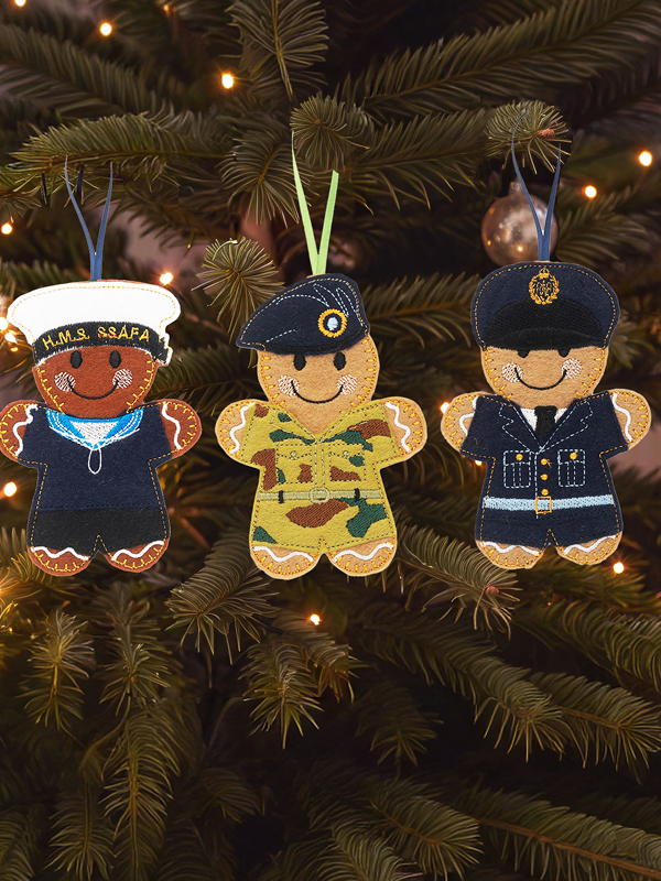 3 gingerbread-style Christmas ornaments of Royal Navy, Army and RAF personnel hanging on a Christmas tree.