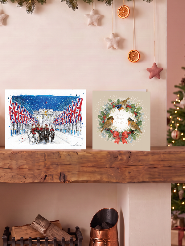 2 Christmas cards on a wooden mantelpiece: Life Guards on Parade and Robins wearing Military hats.